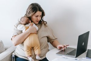 A mom working on her laptop while cuddling her baby